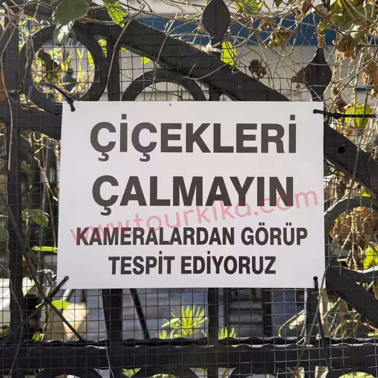 ταμπέλα στα τουρκικά που γράφει Çiçekleri çalmayın. Kameralardan görüp tespit ediyoruz (Μην κλέβετε λουλούδια. Σας βλέπουμε από την κάμερα και σας εντοπίζουμε)