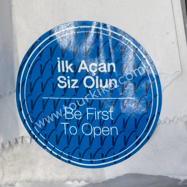 αυτοκόλλητο στα τούρκικα που γράφει İlk açan siz olun (Να είστε ο πρώτος που το ανοίγει = που θα το ανοίξει)