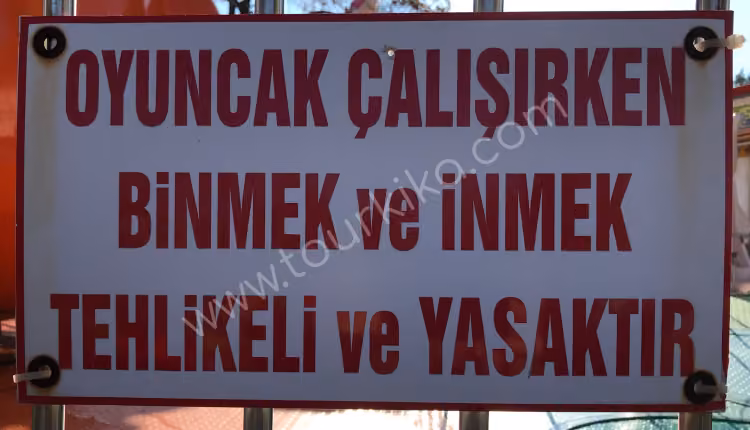 πινακίδα στα τουρκικά γράφει Oyuncak çalışırken binmek ve inmek tehlikeli ve yasaktır (Είναι επικίνδυνη και απαγορεύεται η επιβίβαση και η αποβίβαση όσο λειτουργεί το παιχνίδι)